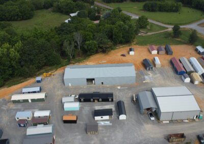 Aerial view of a storage facility with various sheds and greenery in the background.