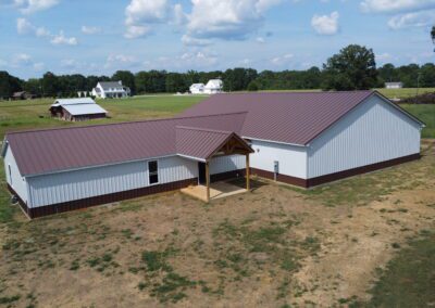 Aerial view of two barn-style buildings with metal roofs and a red pickup truck in front.